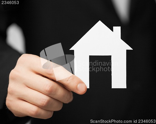 Image of man in suit holding paper house