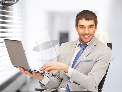 Image of young businessman sitting in chair with laptop