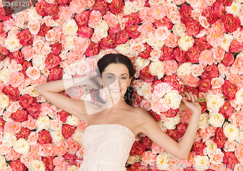 Image of woman with bouquet and background full of roses