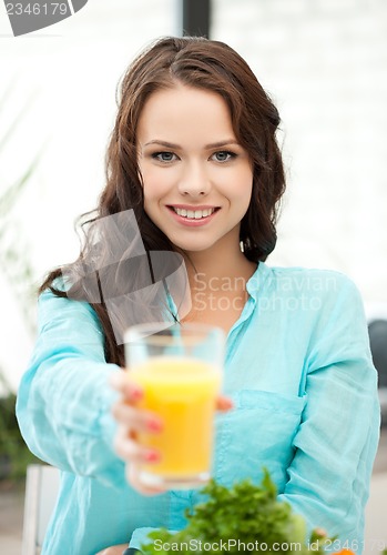 Image of woman holding glass of orange juice