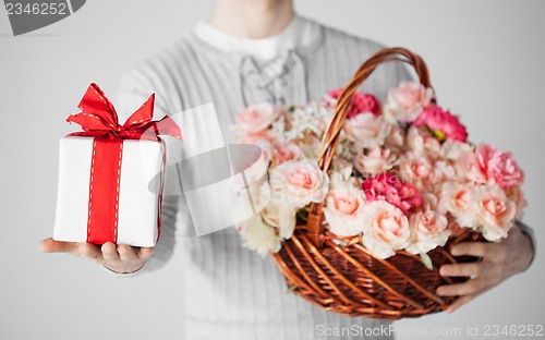 Image of man holding basket full of flowers and gift box