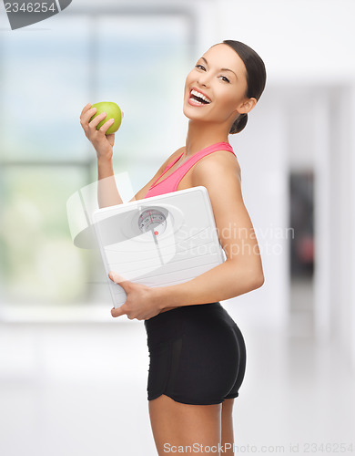 Image of sporty woman with scale and green apple