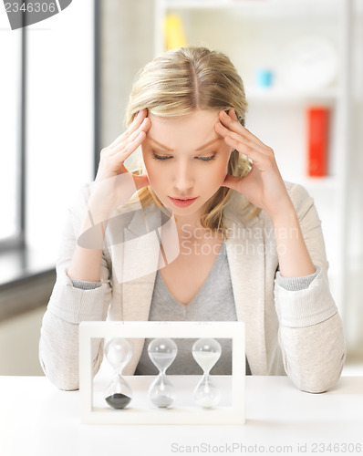 Image of tired woman behind the table with hourgalss