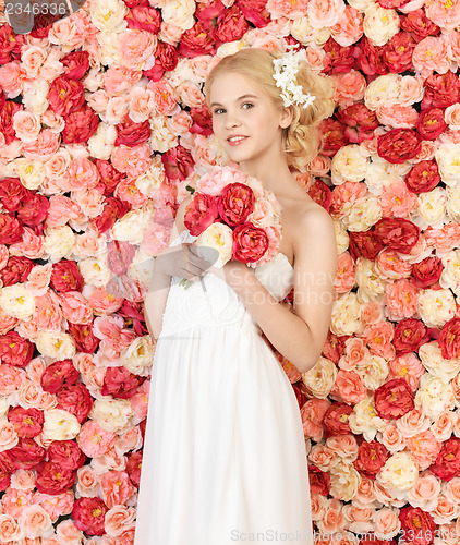 Image of woman with bouquet and background full of roses