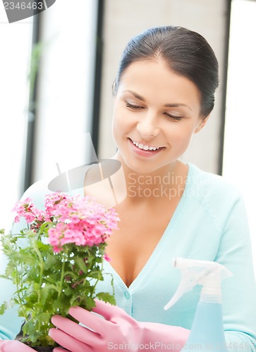 Image of woman holding pot with flower and spray bottle