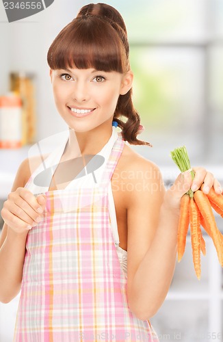 Image of housewife with carrots at the kitchen