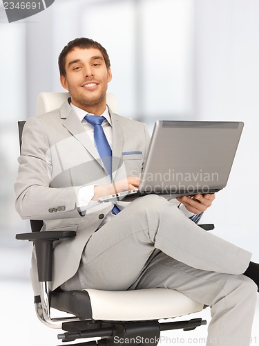 Image of young businessman sitting in chair with laptop