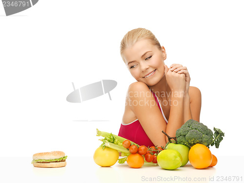 Image of doubting woman with fruits and hamburger