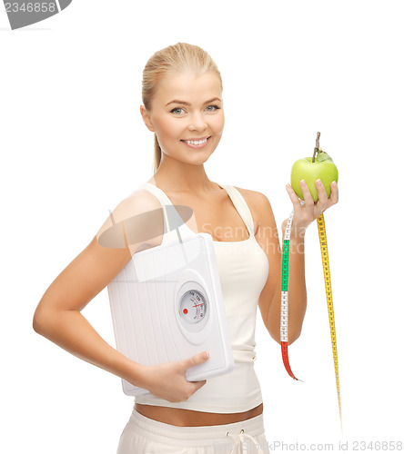 Image of sporty woman with scale, apple and measuring tape