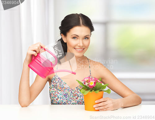 Image of housewife with flower in pot and watering can