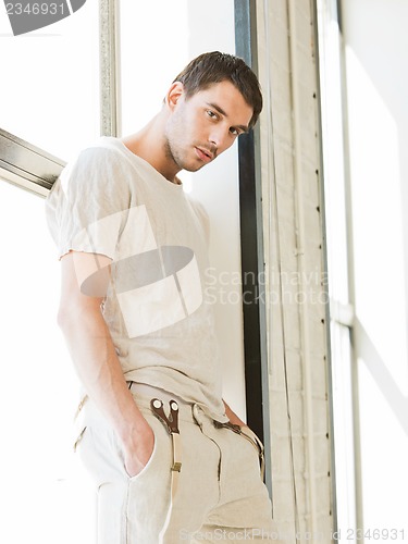 Image of handsome man standing on the windowsill