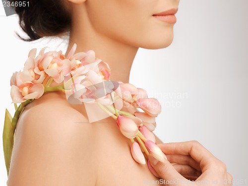 Image of woman's shoulder and hands holding orchid flower