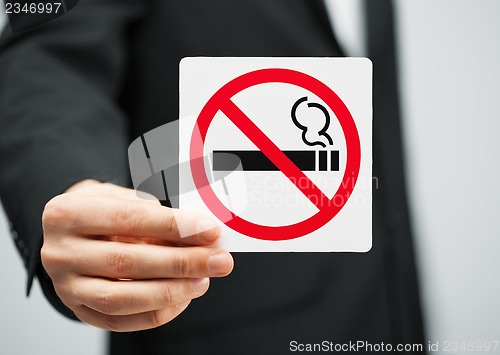 Image of man in suit holding no smoking sign