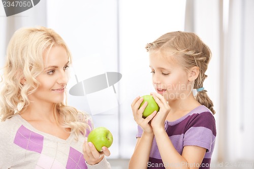 Image of mother and little girl with green apple