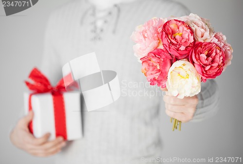 Image of man holding bouquet of flowers and gift box