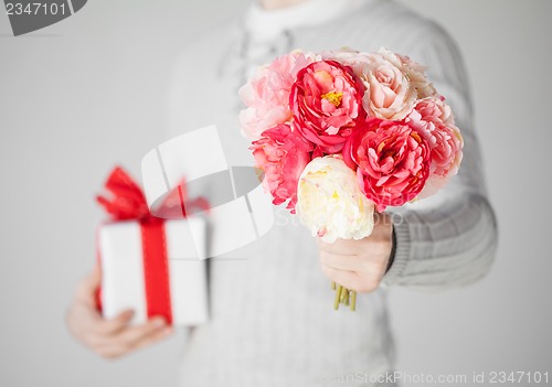 Image of man holding bouquet of flowers and gift box