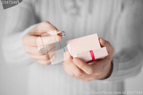 Image of man holding wedding ring and gift box