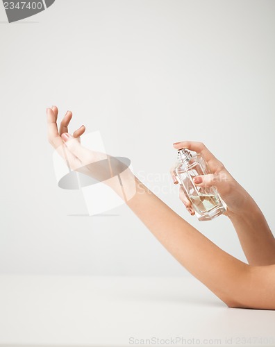 Image of woman hands spraying perfume