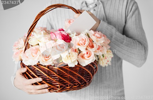 Image of man holding basket full of flowers and postcard