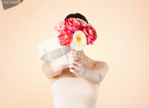 Image of woman holding bouquet of flowers over her face