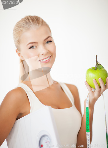Image of sporty woman with scale, apple and measuring tape