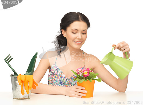 Image of housewife with flower in pot and watering can