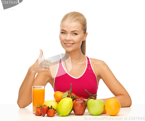 Image of woman with juice and fruits showing thumbs up