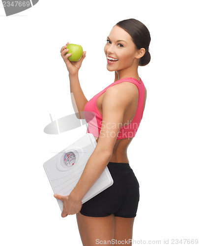 Image of sporty woman with scale and green apple