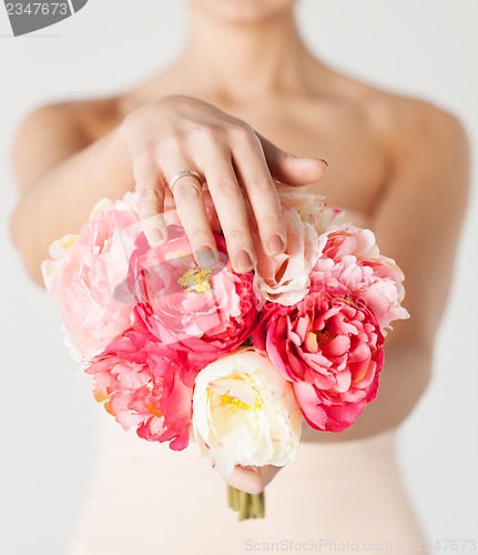 Image of bride with bouquet of flowers and wedding ring