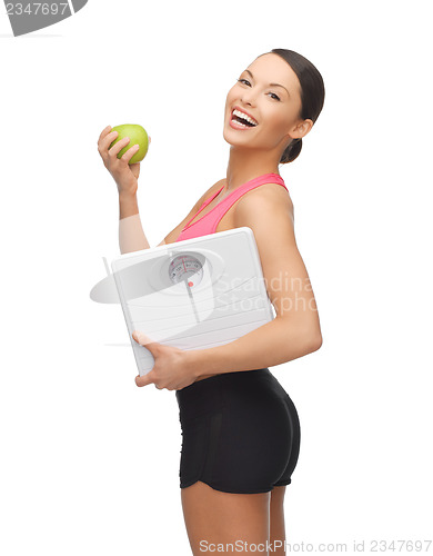 Image of sporty woman with scale and green apple