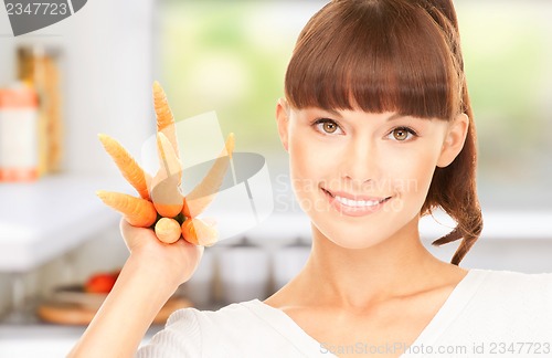 Image of housewife with carrots at the kitchen