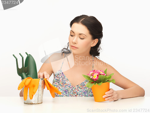 Image of housewife with flower in pot and gardening set