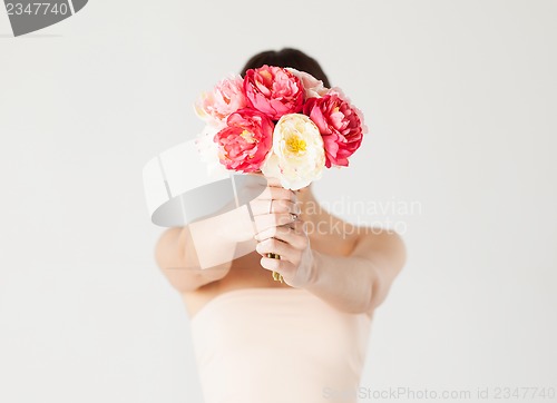 Image of woman holding bouquet of flowers over her face
