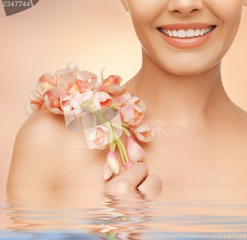 Image of woman's shoulder and hands holding orchid flower