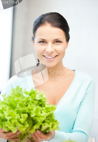 Image of woman in the kitchen with green salad leaves