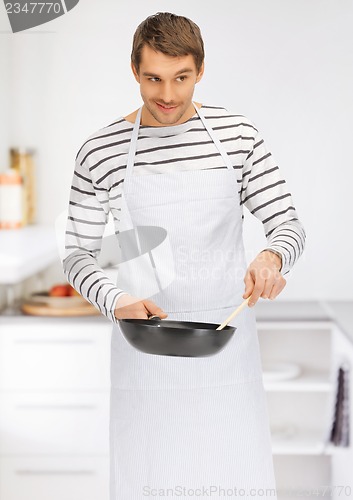 Image of handsome man with pan at kitchen