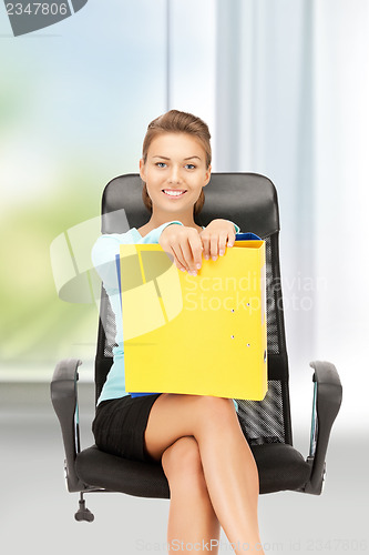 Image of young businesswoman with folders sitting in chair