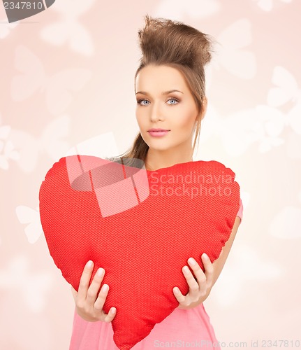 Image of happy and smiling woman with heart-shaped pillow