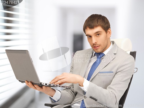 Image of young businessman sitting in chair with laptop