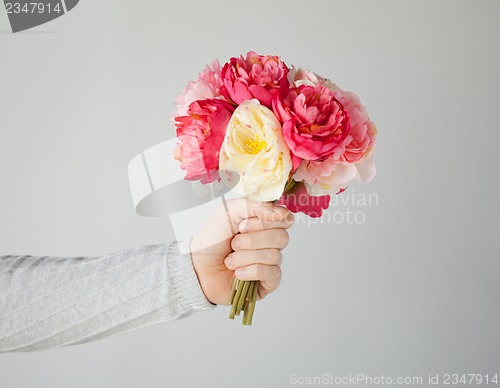 Image of man's hand giving bouquet of flowers