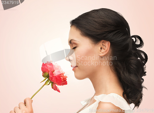 Image of smiling woman smelling flower