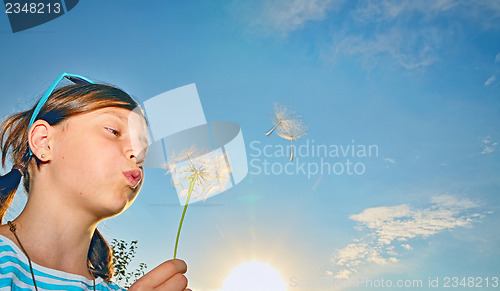 Image of Young girl blowing dandelion