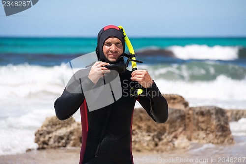 Image of male diver with diving suit snorkel mask fins on the beach