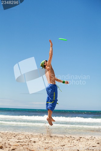 Image of attractive man playing frisby on beach in summer