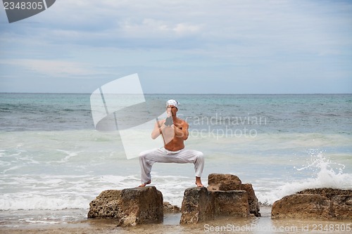 Image of healthy man doing pilates yoga meditation on beach summer