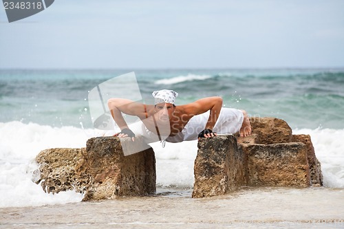 Image of healthy man doing pilates yoga meditation on beach summer