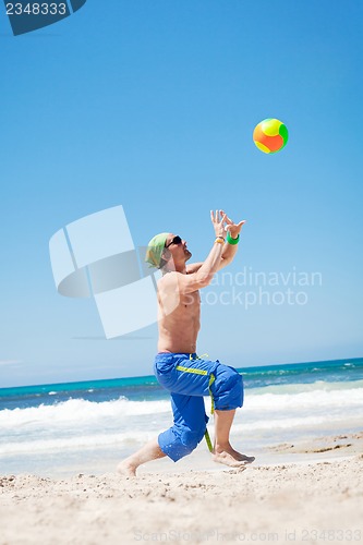 Image of attractive young man playing volleyball on the beach