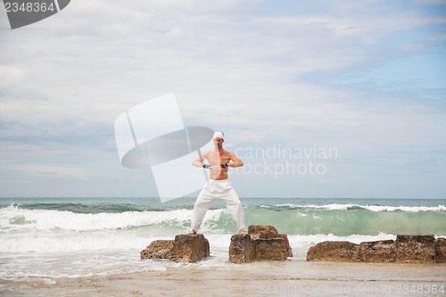 Image of healthy man doing pilates yoga meditation on beach summer