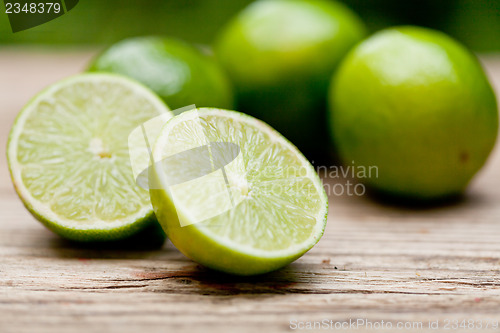 Image of green fresh lime on wooden table macro closeup outdoor