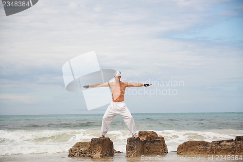 Image of healthy man doing pilates yoga meditation on beach summer